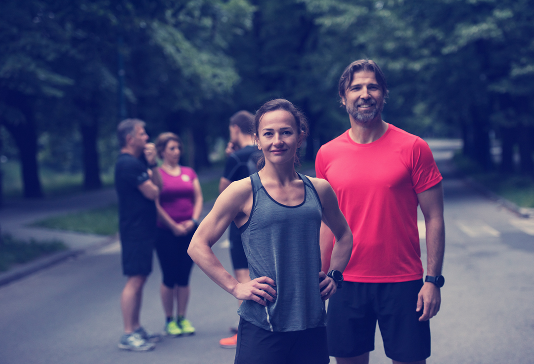 portrait of a healthy jogging couple with the rest of their running team in the background