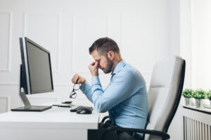 Tired businessman from heavy workload sitting at the desk