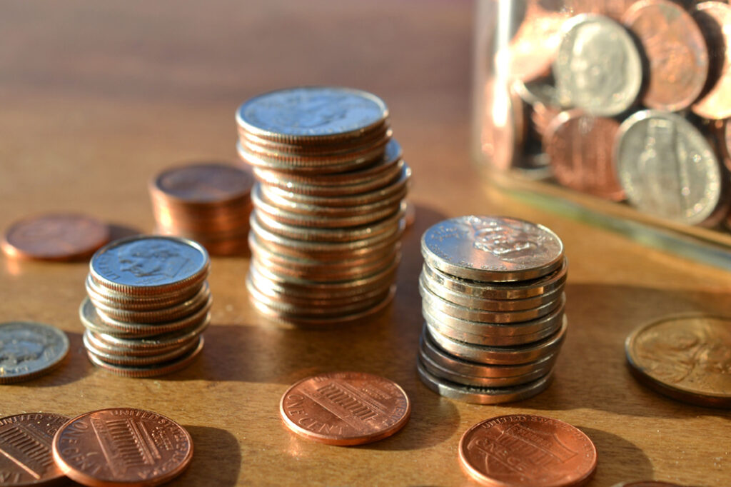 A table with stacks of coins and a glass
