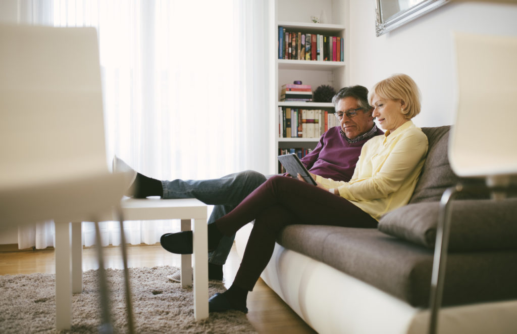 A man and woman sitting on the couch looking at something.