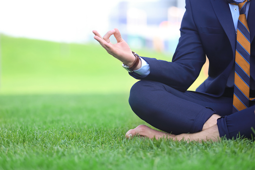 A person in business attire sitting on the grass