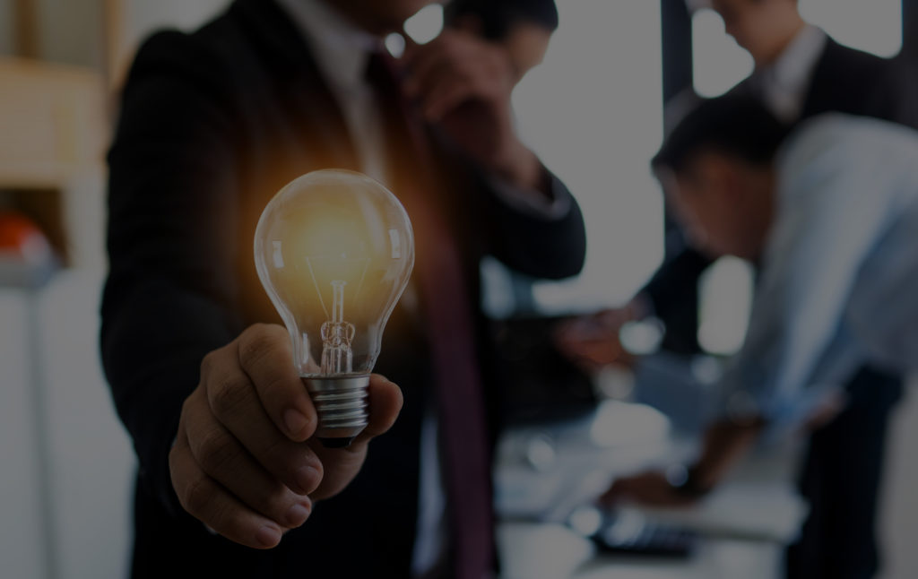 A person holding an illuminated light bulb in their hand.